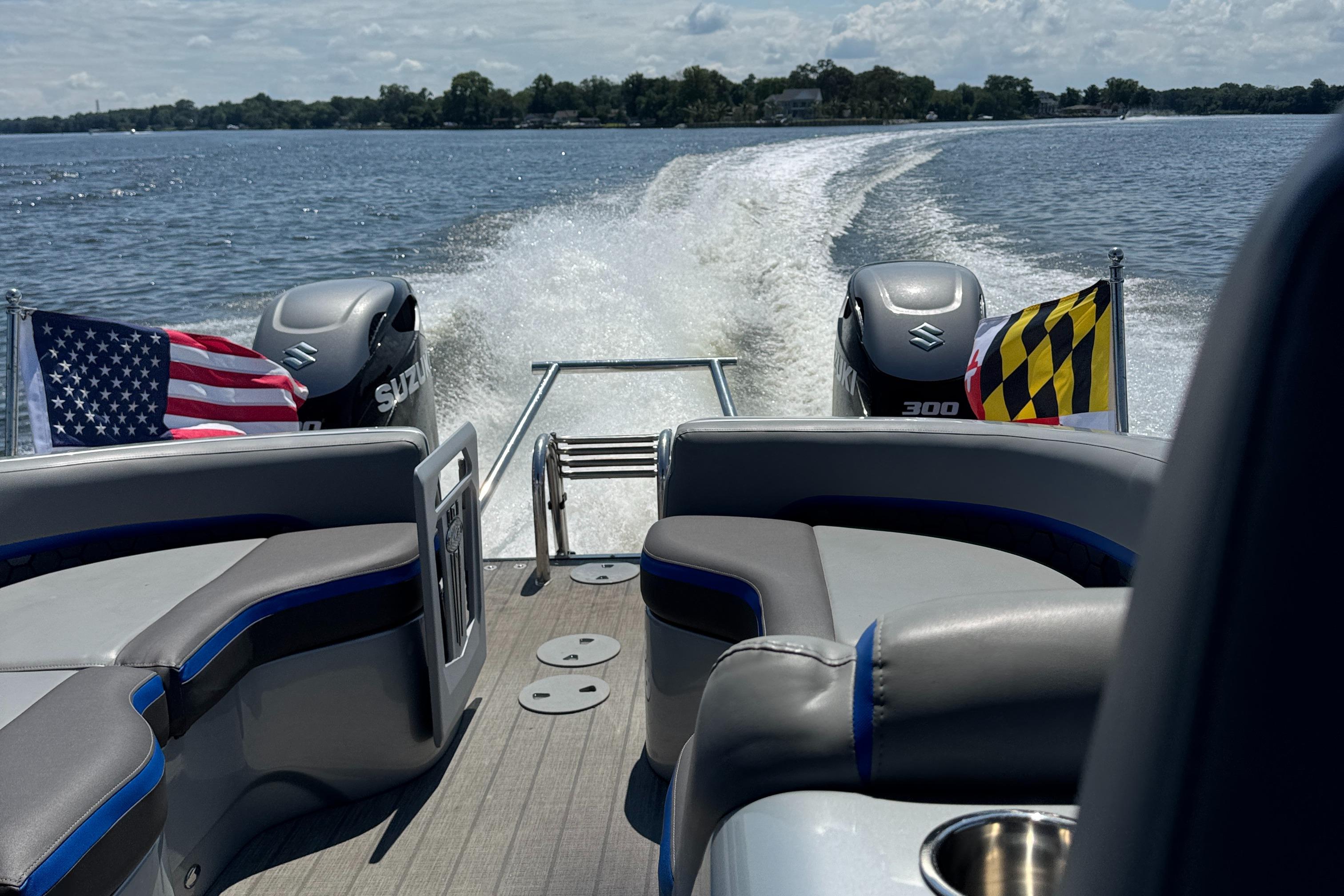 Manitou 25 XT SRS 2021 Manitou 25 XT SRS boat cruising on a lake with flags and Suzuki engines.
