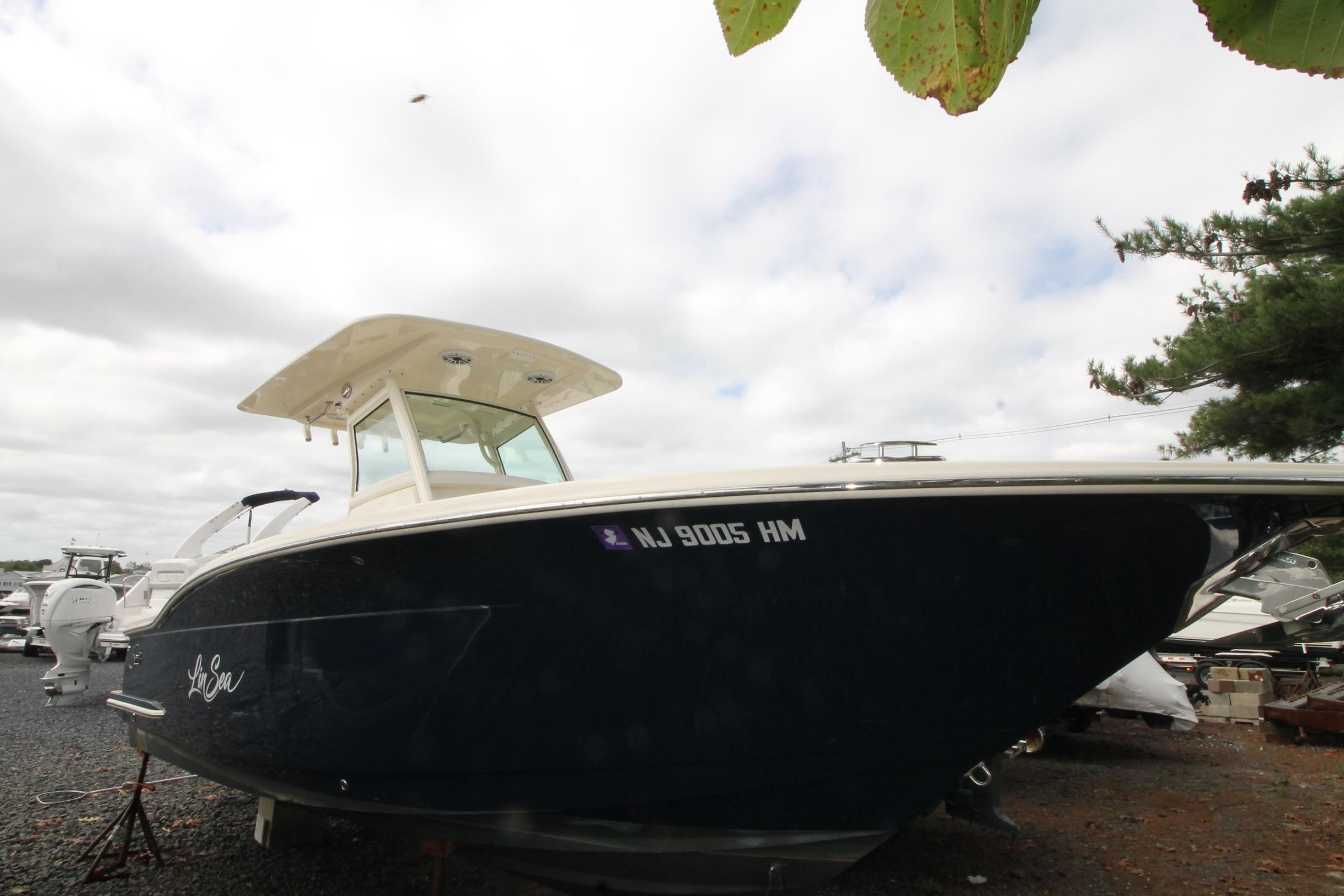 Scout 255 LXF 2020 Scout 255 LXF boat on display, dark hull, parked outdoors.
