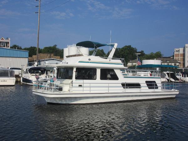 Gibson 44 Classic 1995 Gibson 44 Classic houseboat docked in a marina under a clear blue sky.