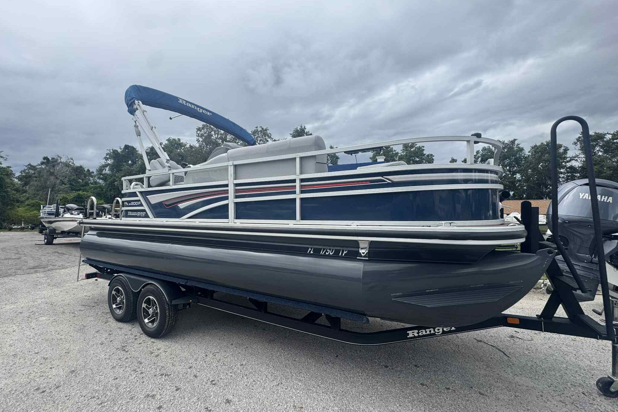 Ranger Reata 200F 2019 Ranger Reata 200F pontoon boat on trailer, parked outdoors under cloudy sky.
