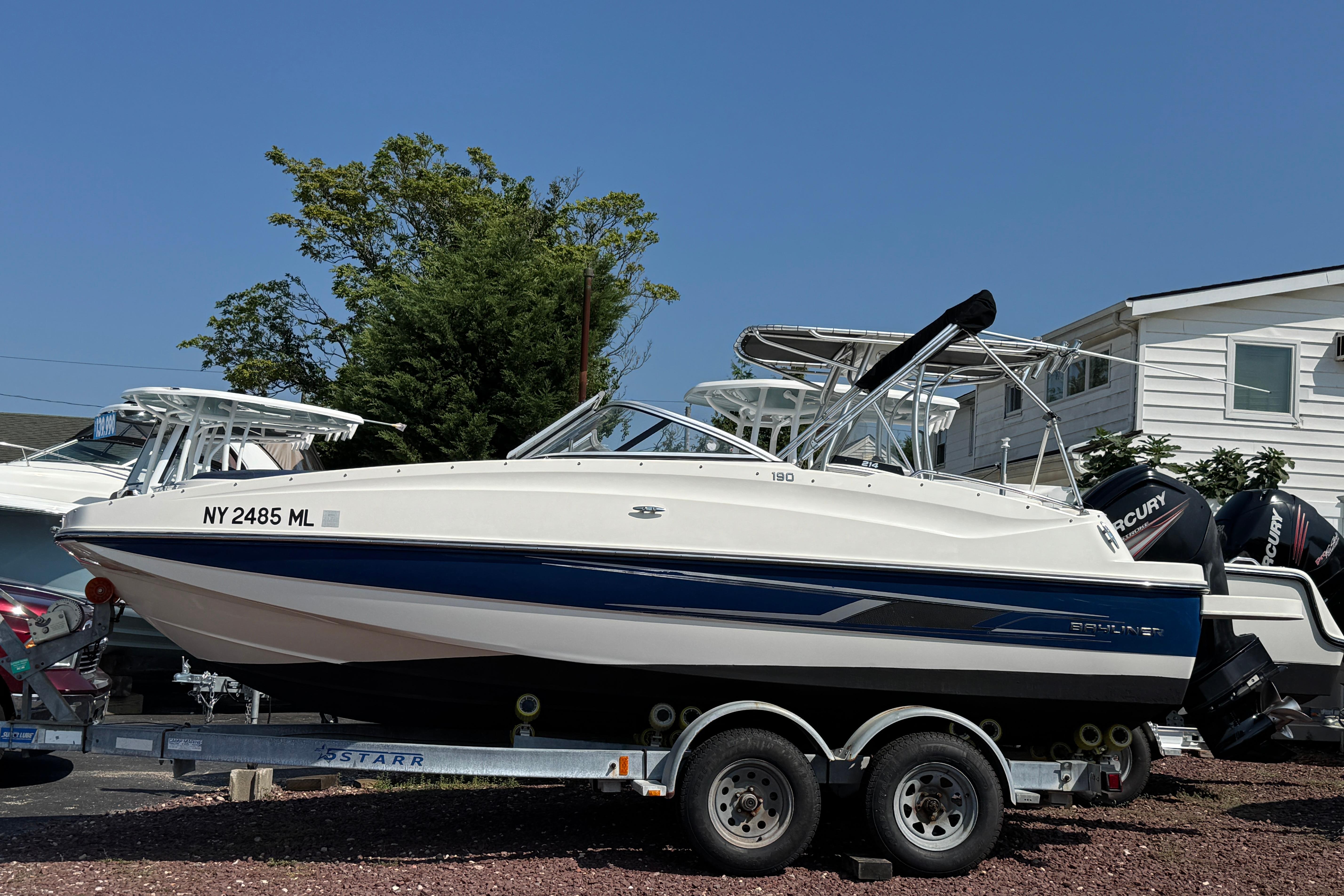 Bayliner 190 Deck Boat 2015 Bayliner 190 Deck Boat on trailer, parked outdoors, with clear blue sky.