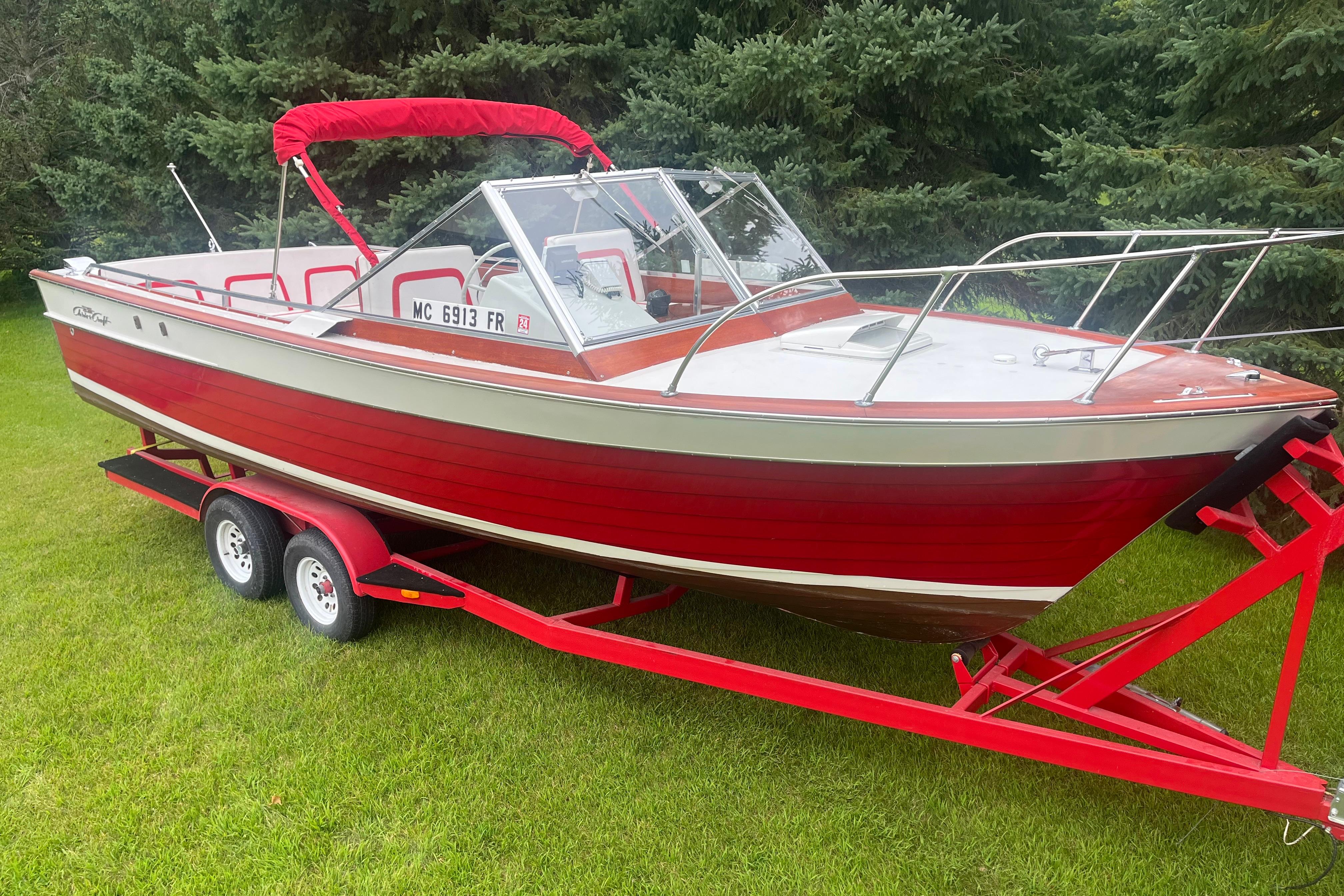 Chris-Craft Sea Skiff 1964 Chris-Craft Sea Skiff boat on red trailer, parked on grass.