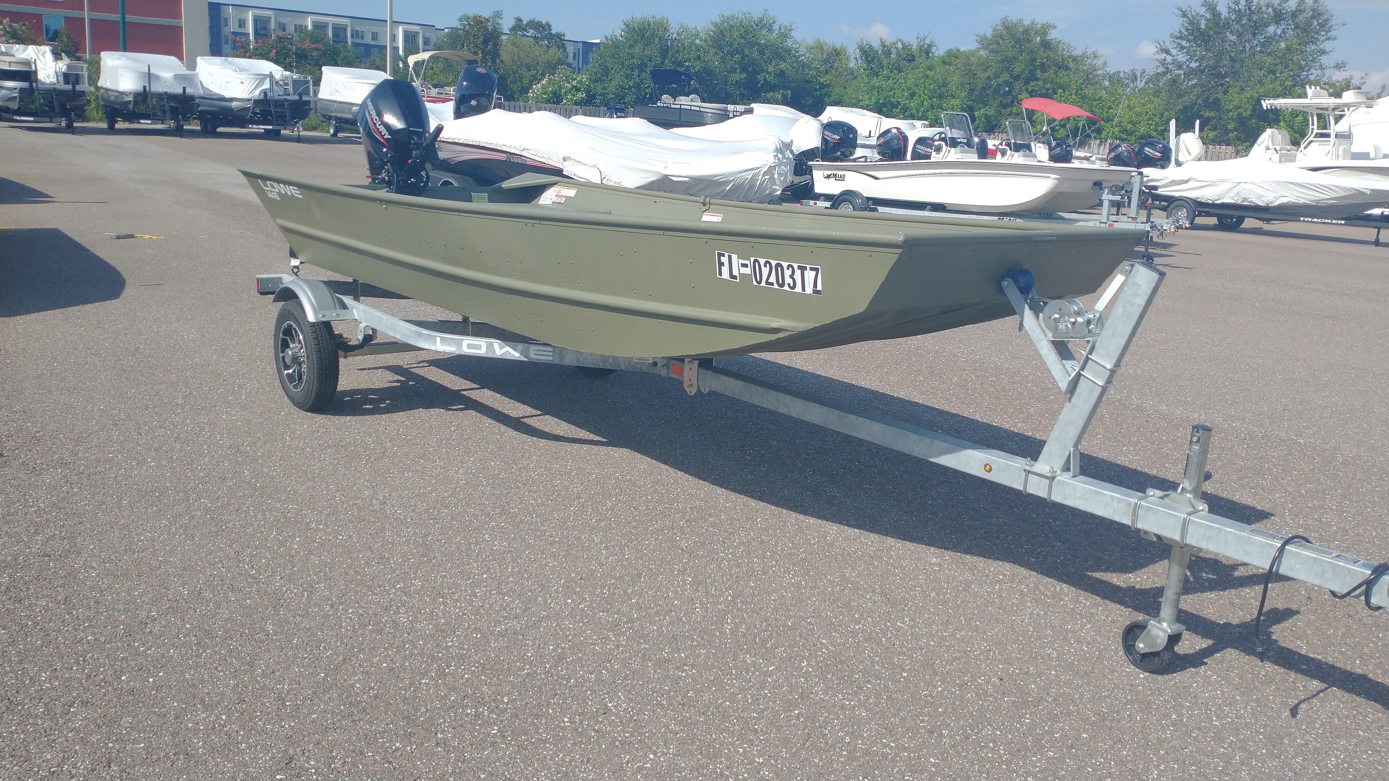 Lowe Jon L1448 2025 Lowe Jon L1448 boat on trailer in parking lot, surrounded by other boats.