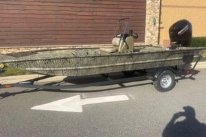 Tracker Grizzly 1860 CC 2026 Tracker Grizzly 1860 CC boat on trailer, camo design, parked outdoors.