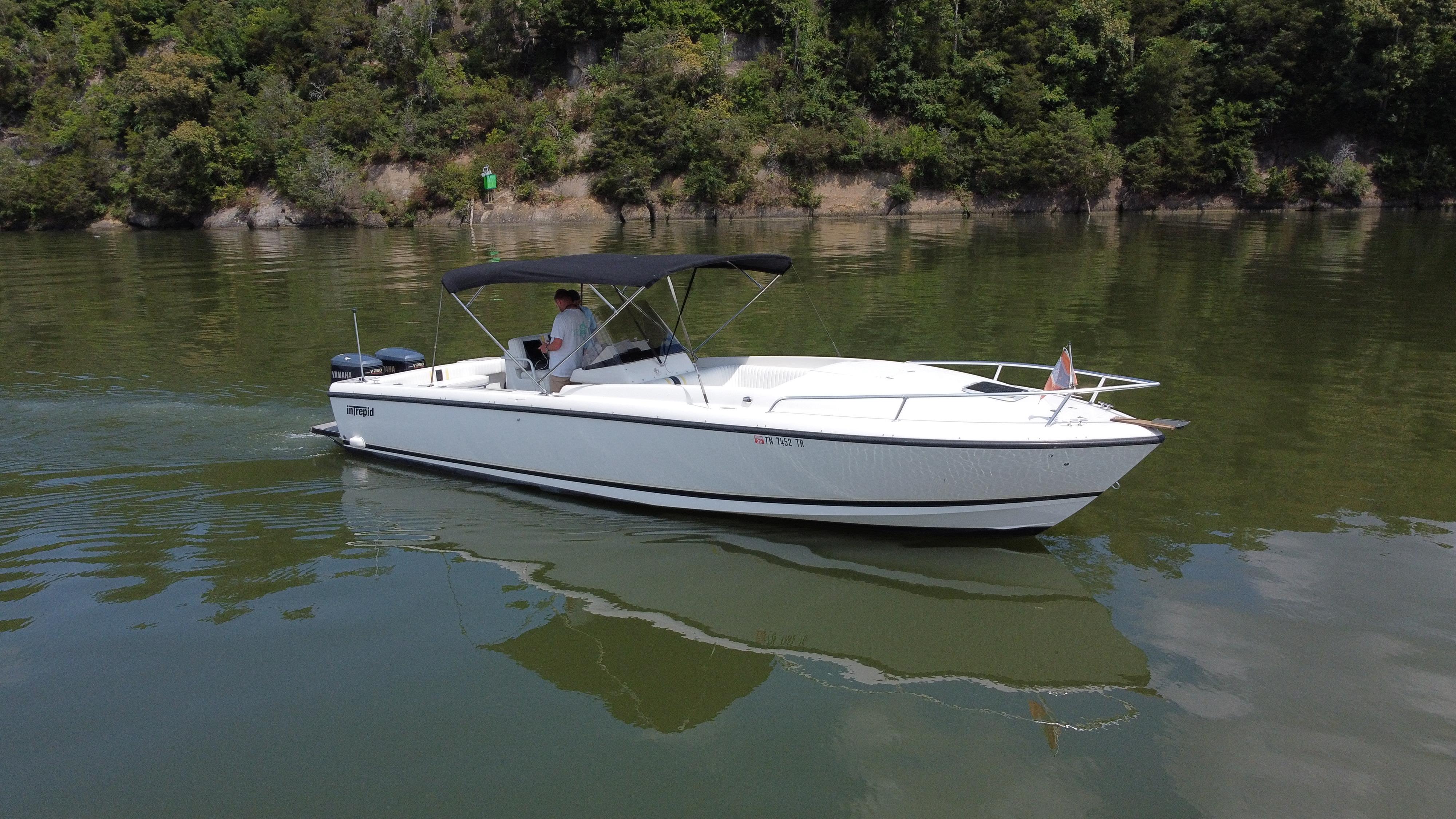 Intrepid 323 Cuddy 2002 Intrepid 323 Cuddy boat cruising on a calm lake with lush green shoreline.