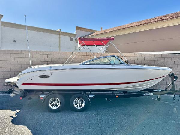 Cobalt 220S 2017 Cobalt 220S boat with red canopy on trailer, parked outdoors.