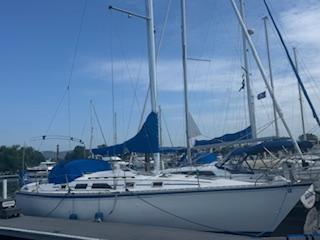 Hunter 34 1986 Hunter 34 sailboat docked at marina with blue covers and clear sky.