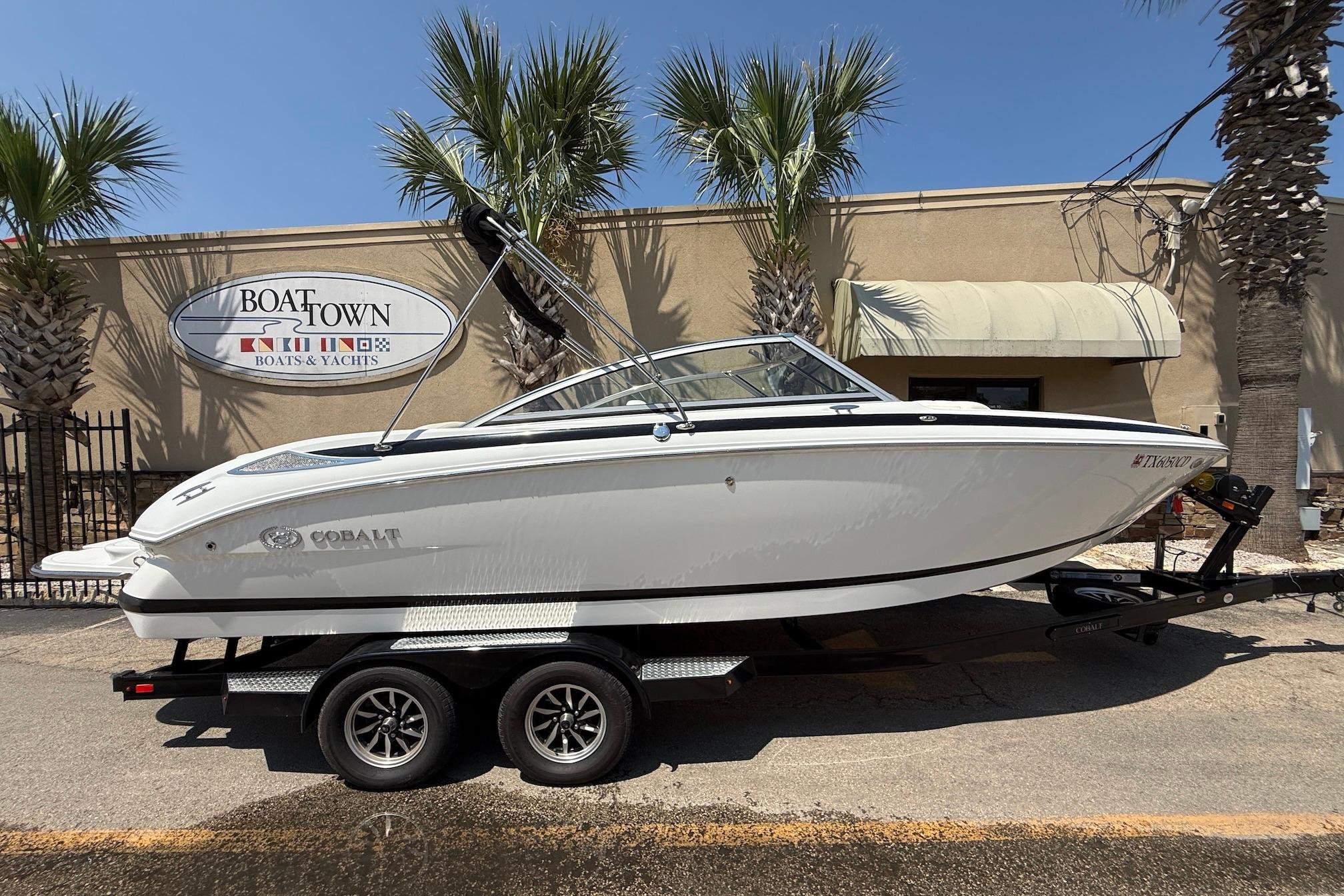 Cobalt 232 2013 Cobalt 232 boat on trailer at Boat Town dealership, sunny day.