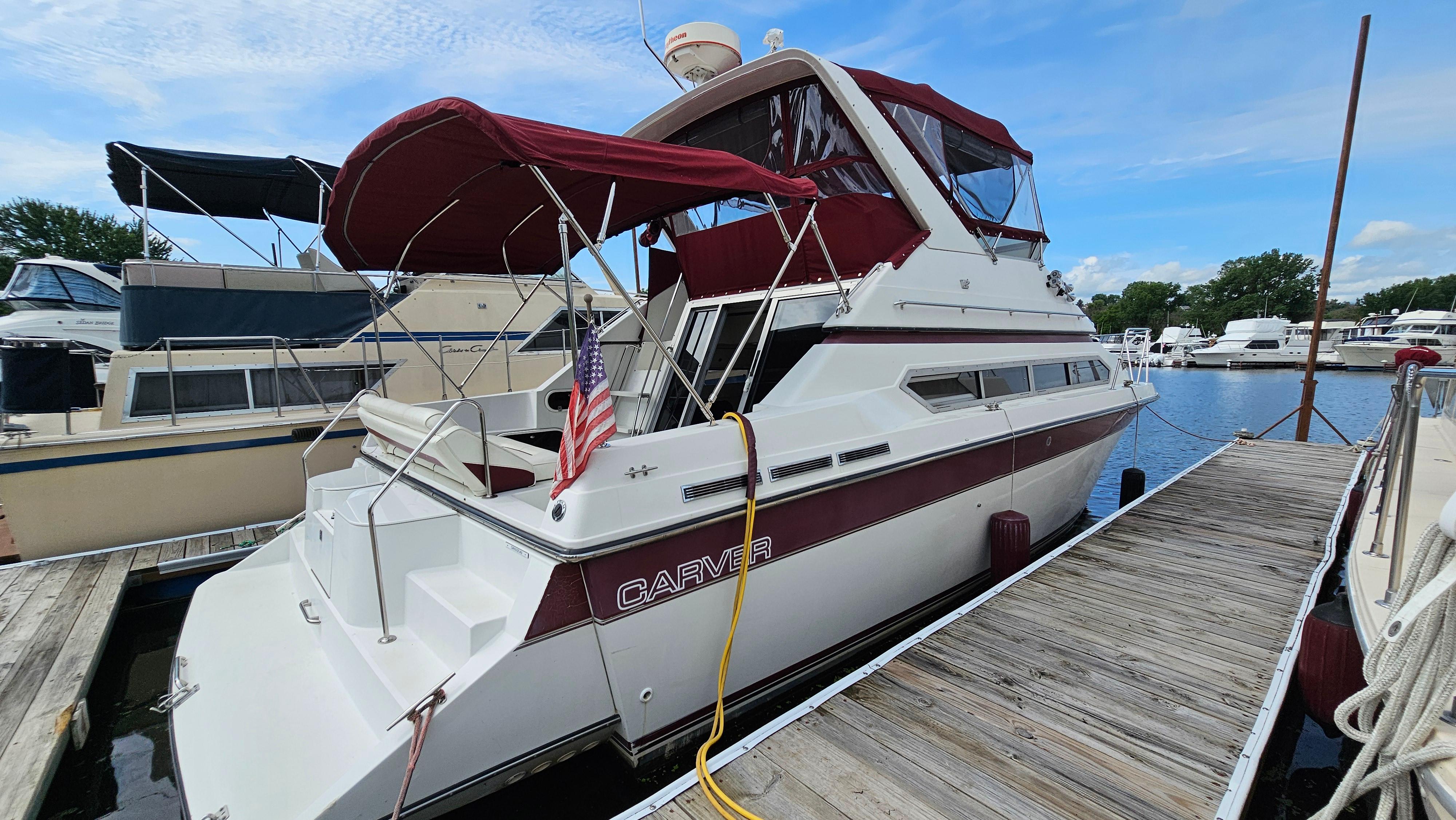 Carver 38 Santego 1989 Carver 38 Santego yacht docked, featuring maroon canopy and American flag.