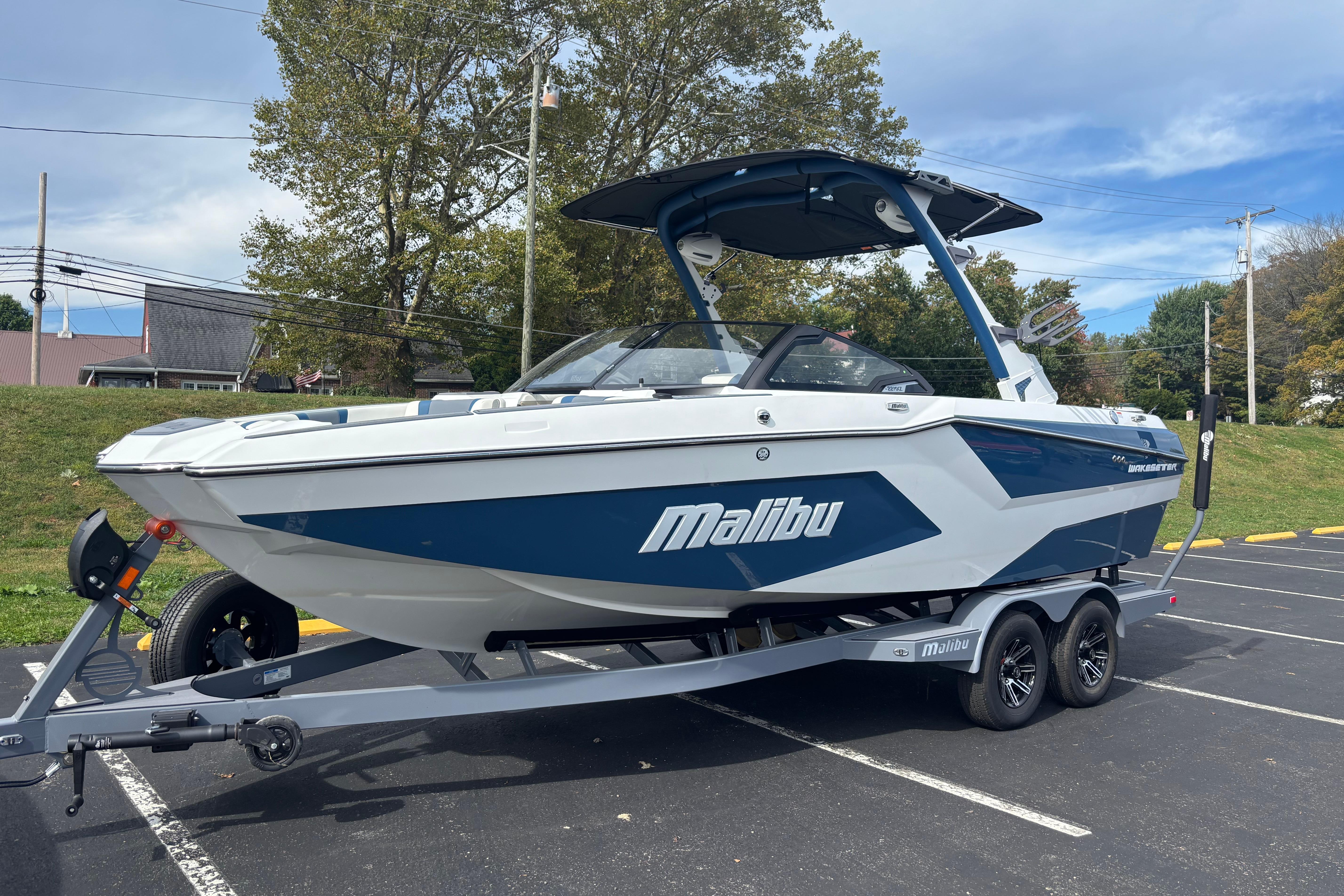 Malibu Wakesetter 22 MXZ 2025 Malibu Wakesetter 22 MXZ boat on trailer in parking lot.