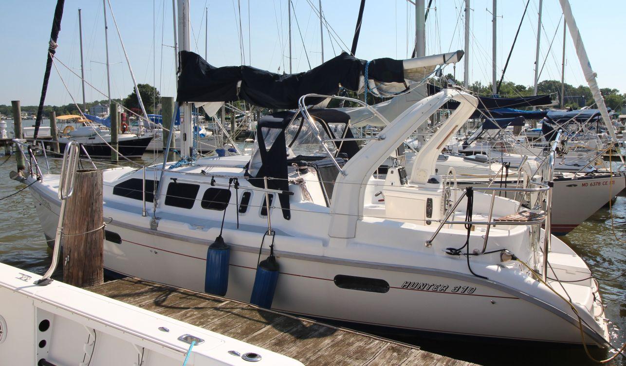 Hunter 310 1997 Hunter 310 sailboat docked at marina, featuring sleek design and white hull.