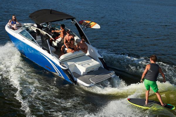 Cobalt R5 WSS Surf Manufacturer Provided Image: 2016 Cobalt R5 WSS Surf boat with people wake surfing on a lake.