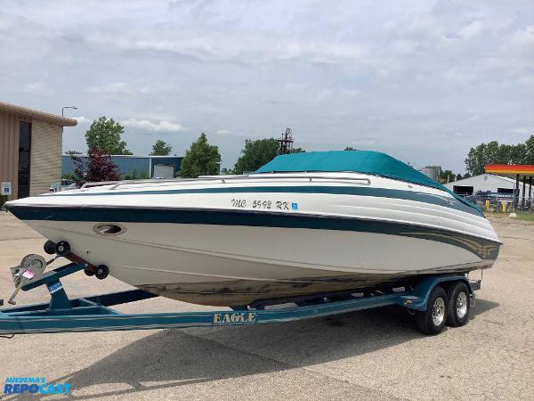 Crownline 266 CCR 1999 Crownline 266 CCR boat on trailer, teal cover, parked outdoors.
