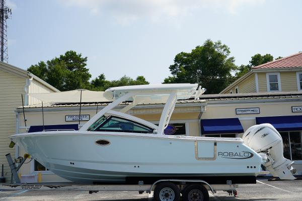Robalo R257 2025 Robalo R257 boat on trailer, parked outside a building with trees in the background.
