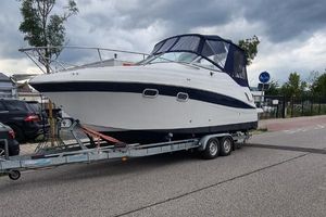 Four Winns 248 TOP MIT DIESEL und TRAILER 2001 Four Winns 248 boat on trailer, parked on street under cloudy sky.