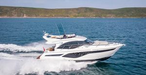 Princess F50 2024 Princess F50 yacht cruising on open water with scenic coastline backdrop.
