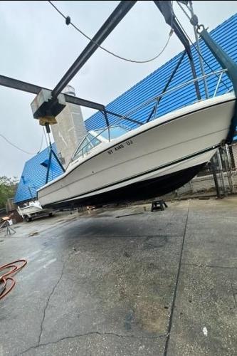 Pursuit 2460 Denali 1995 Pursuit 2460 Denali boat suspended in a boatyard with blue building background.