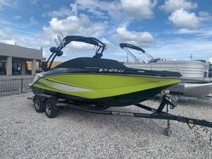 Scarab 215 2014 Scarab 215 boat on trailer, lime green and black, parked outdoors.
