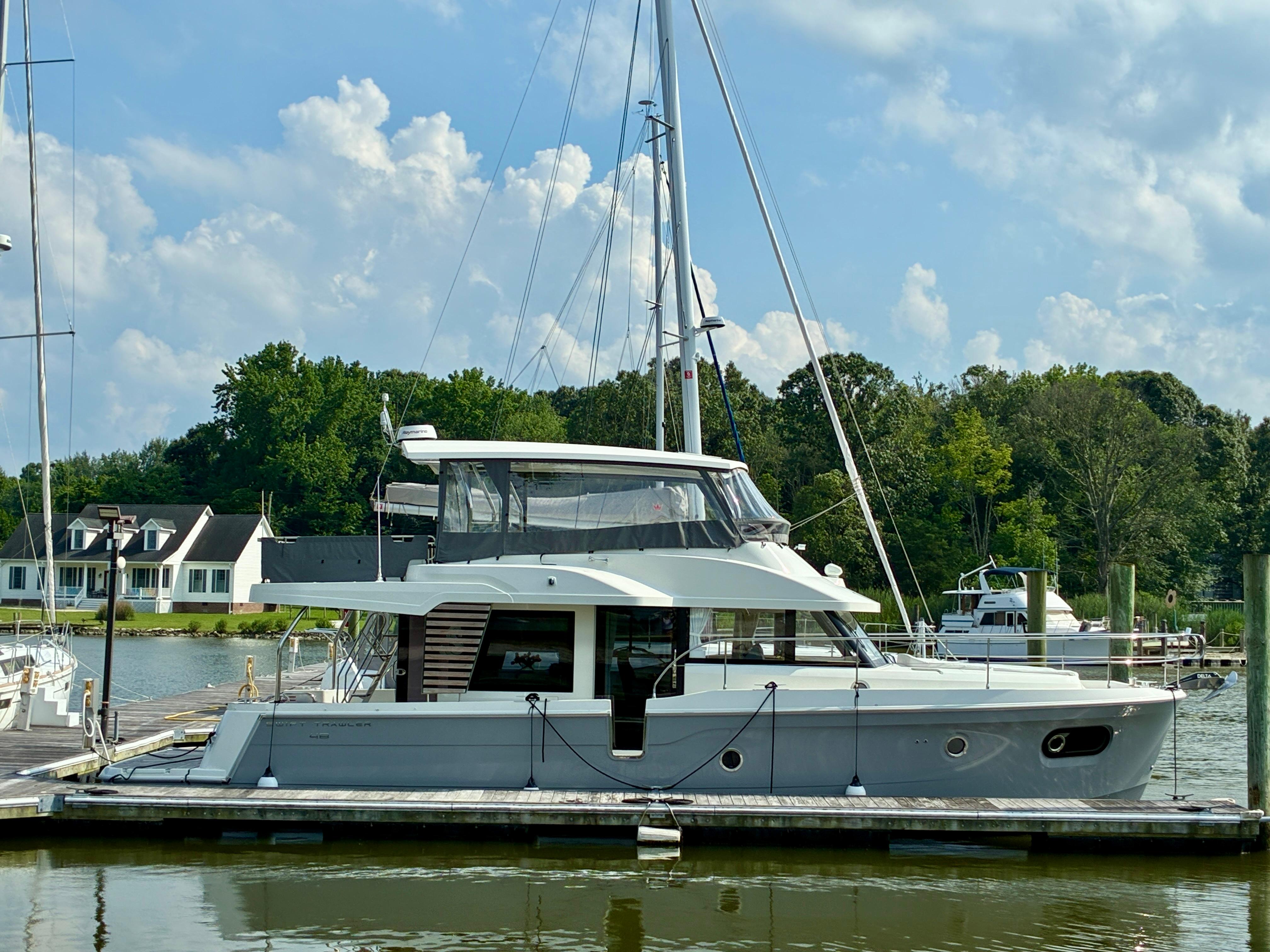 Beneteau Swift Trawler 48 2024 Beneteau Swift Trawler 48 docked at a marina under a cloudy sky.