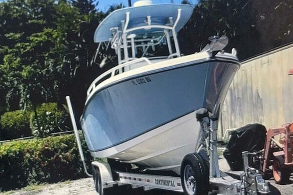 Mako 284 CC 2017 Mako 284 CC boat on trailer, parked outdoors with lush greenery background.