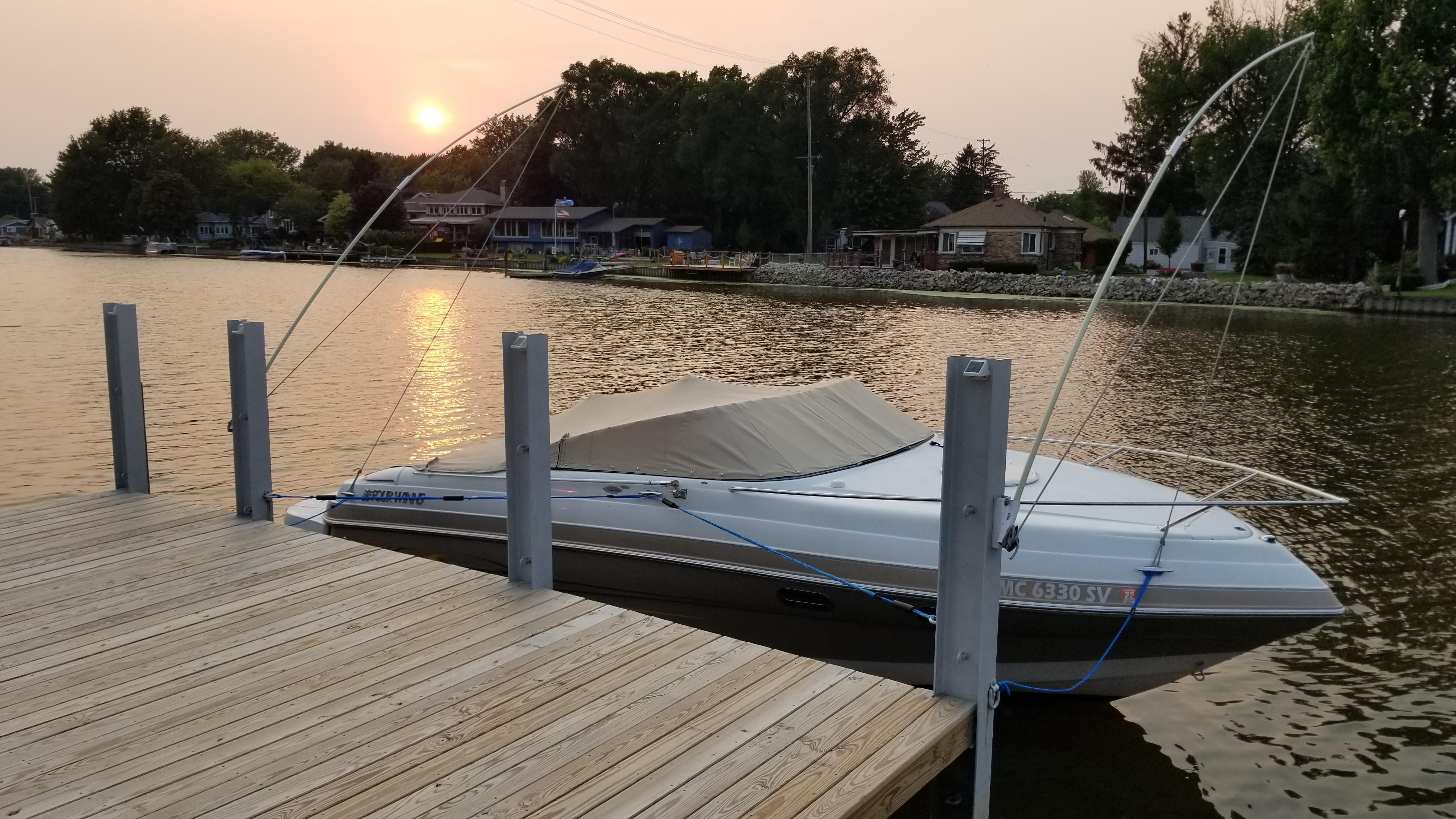 Four Winns 245 Sundowner 2005 Four Winns 245 Sundowner boat docked at sunset on a calm lake.
