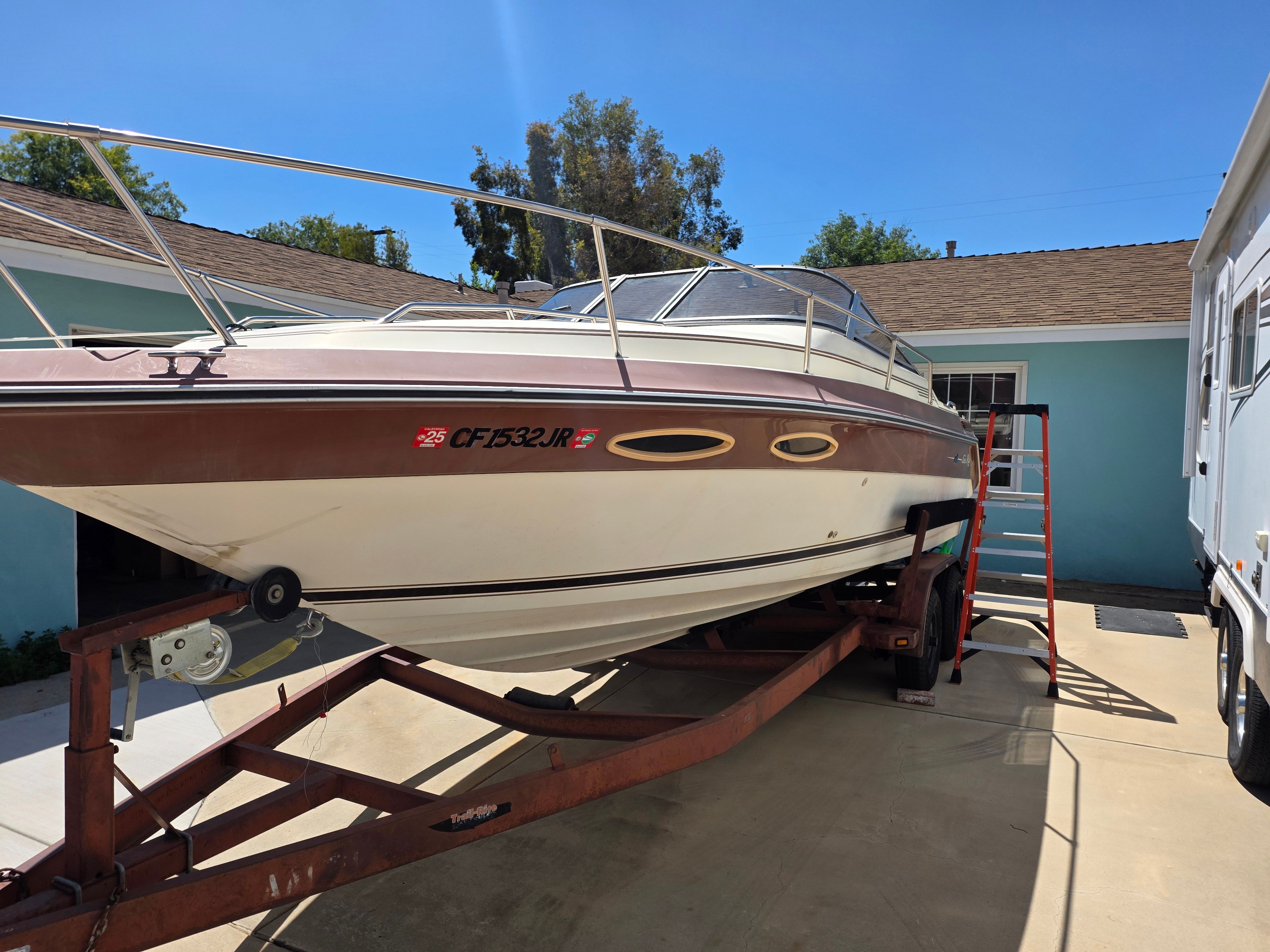 Sea Ray CuddyCabin 1995 Sea Ray Cuddy Cabin boat on trailer in driveway, sunny day.