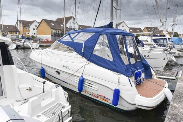 Cranchi Giada 1999 Cranchi Giada boat docked in marina, featuring blue canopy and white hull.