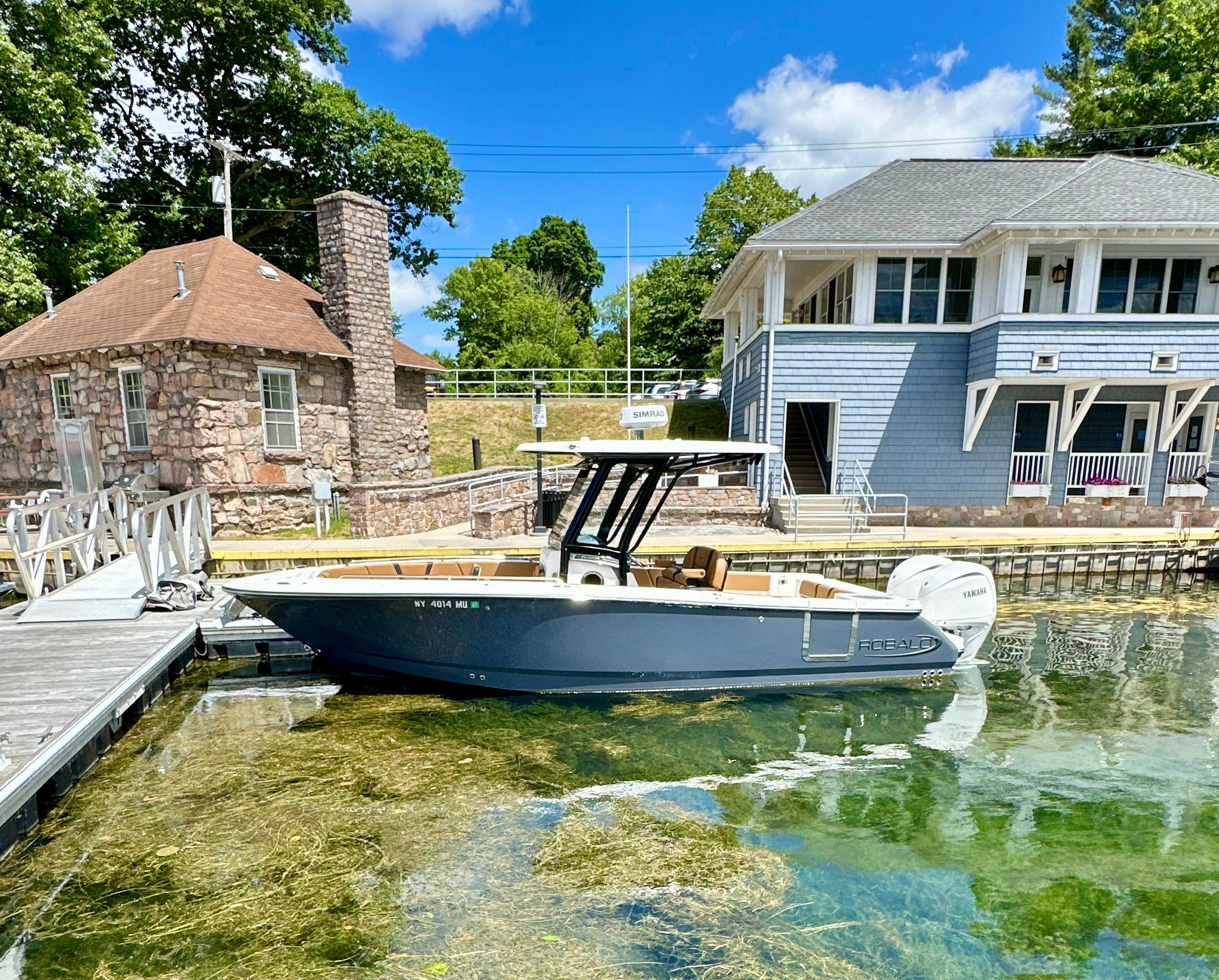 Robalo R250 Center Console 2024 Robalo R250 Center Console boat docked by lakeside buildings.