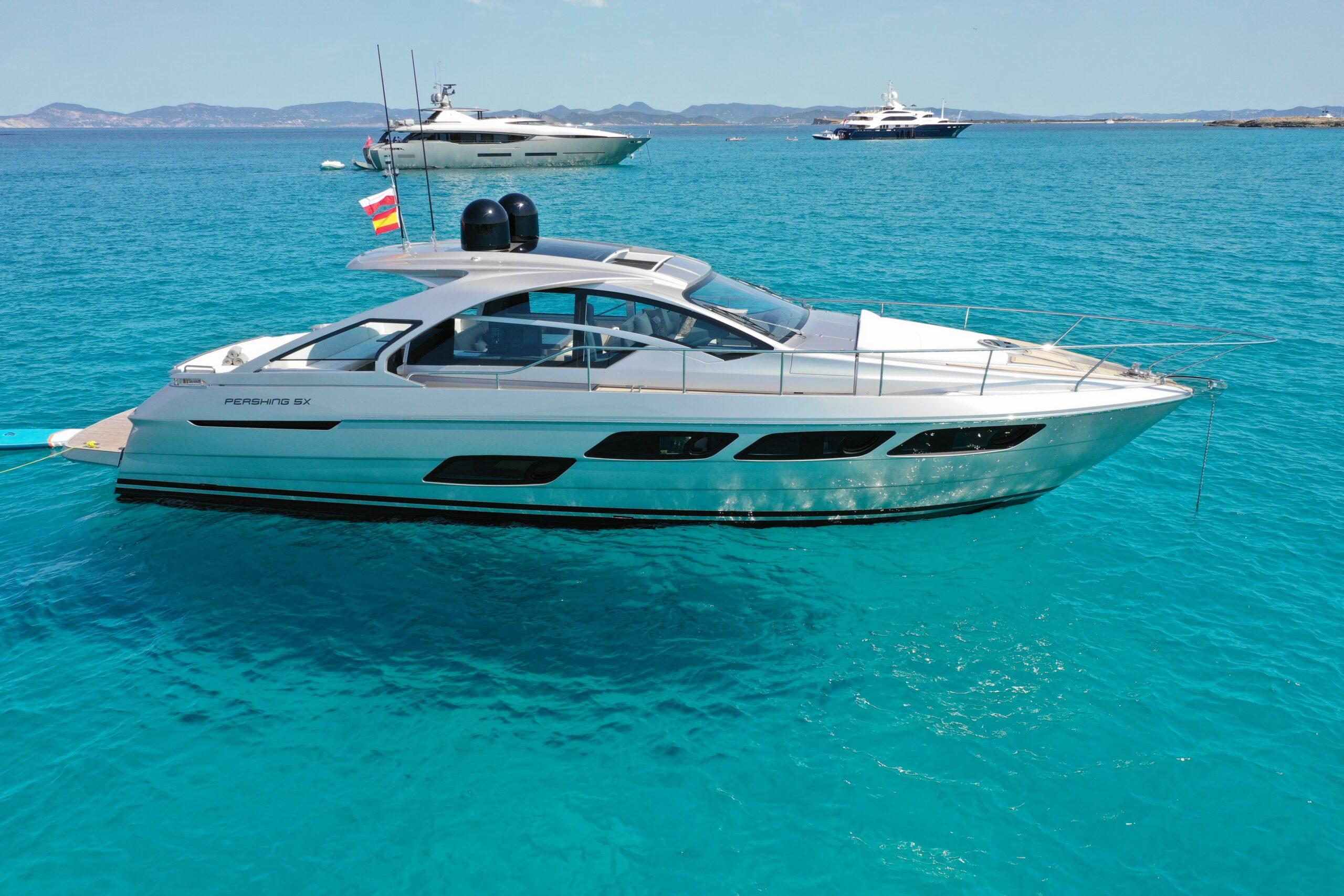 Pershing 5x 2021 Pershing 5x yacht on turquoise water, with distant boats and scenic coastline.