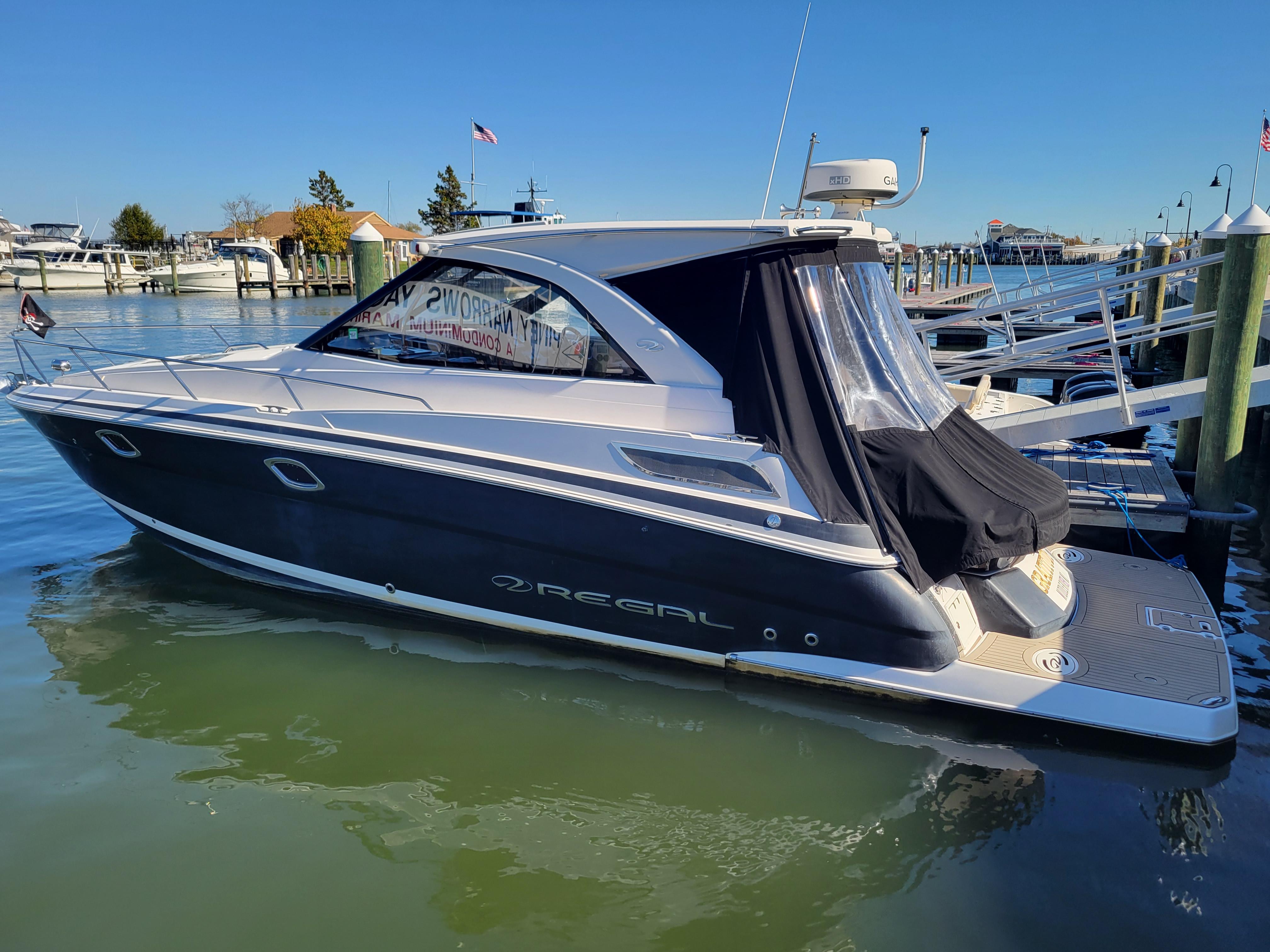 Regal 35 Sport Coupe 2015 Regal 35 Sport Coupe boat docked in marina, clear blue sky background.