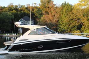 Regal 35 Sport Coupe 2015 Regal 35 Sport Coupe boat on a serene lake with lush trees.