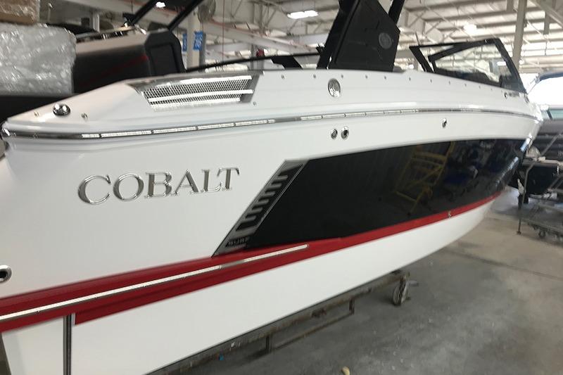 Cobalt R4 Surf 2024 Cobalt R4 Surf boat in showroom, sleek design with white and black exterior.