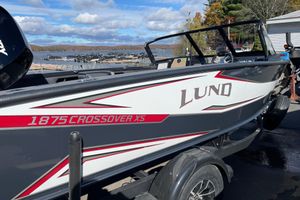 Lund 1875 Crossover XS 2026 Lund 1875 Crossover XS boat on trailer by lakeside, under clear sky.