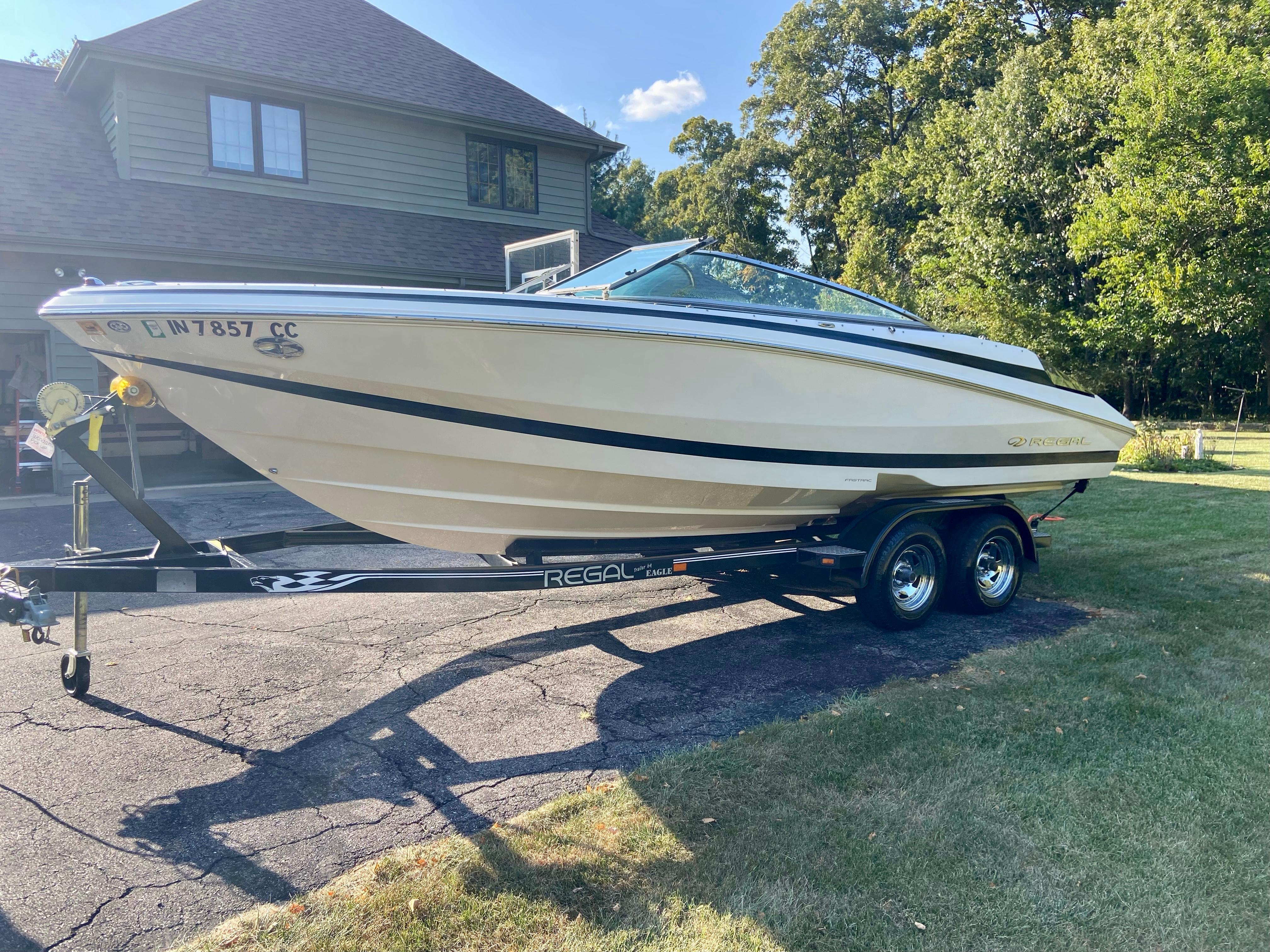Regal 2200 Bowrider 2005 Regal 2200 Bowrider boat on trailer, parked in driveway, surrounded by trees.