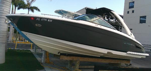 Regal 2800 Bowrider 2017 Regal 2800 Bowrider boat on a lift near palm trees and a building.