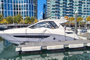 Sea Ray Sundancer 350 Coupe 2019 Sea Ray Sundancer 350 Coupe docked at a marina with modern buildings in the background.