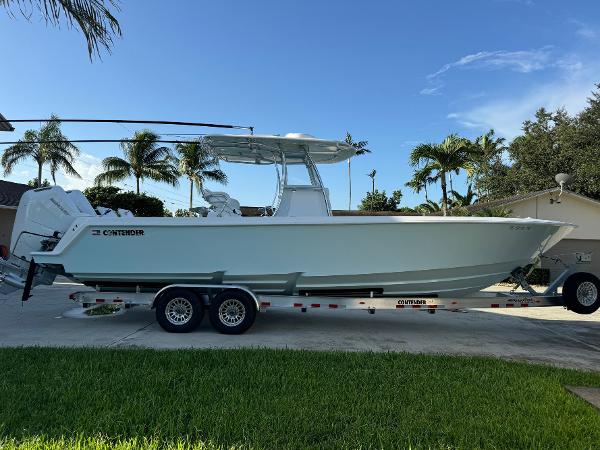 Contender 32 ST 2024 Contender 32 ST boat on trailer, parked outdoors with palm trees in background.