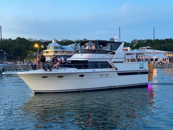 Carver 48 Californian 1990 Carver 48 Californian yacht cruising near a marina at dusk.