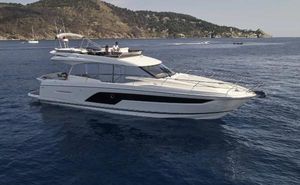 Prestige 590 Luxury 2021 Prestige 590 yacht cruising on serene blue waters near a scenic coastline.