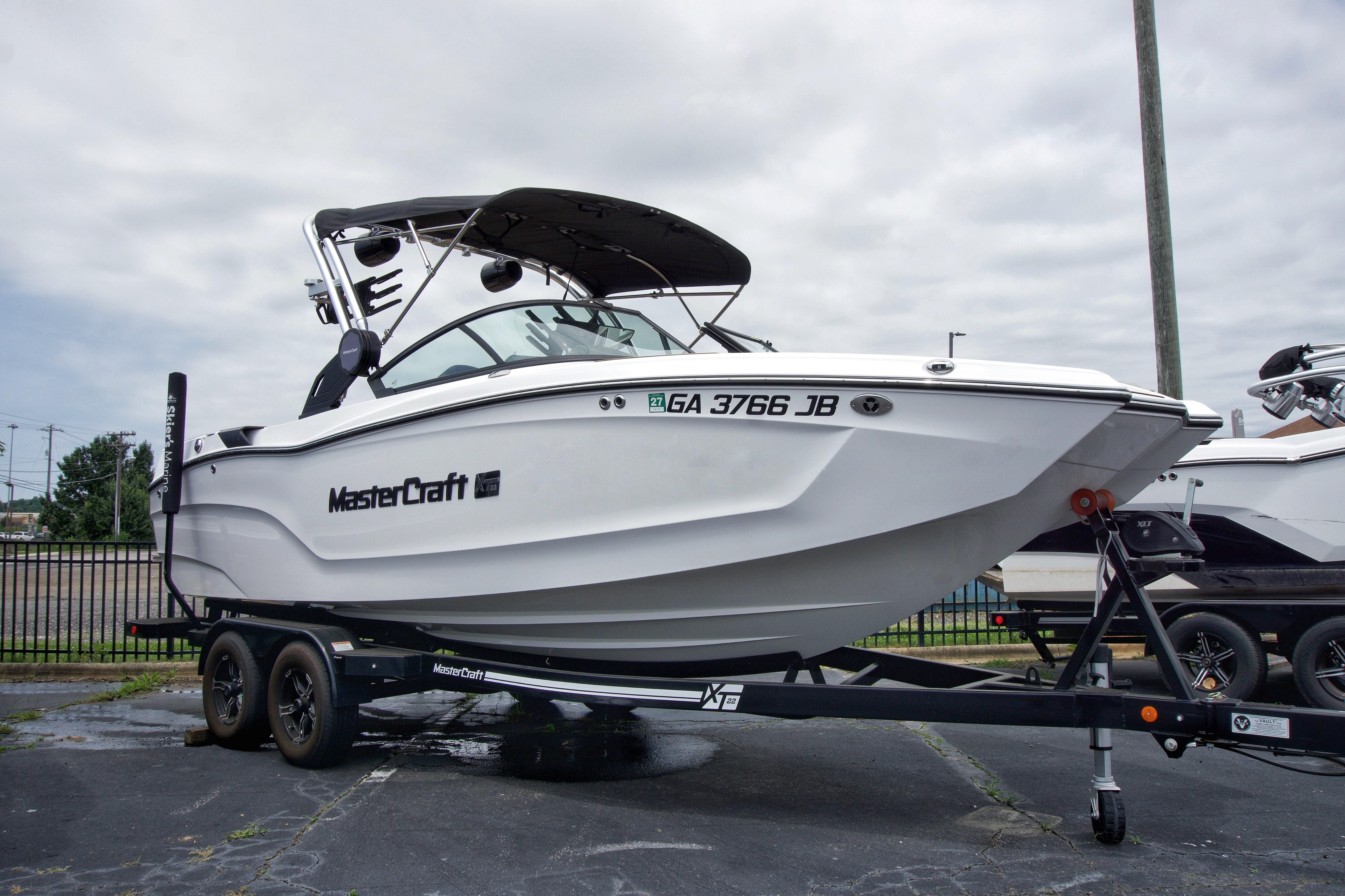 MasterCraft XT22 2022 MasterCraft XT22 boat on trailer, parked outdoors under cloudy sky.