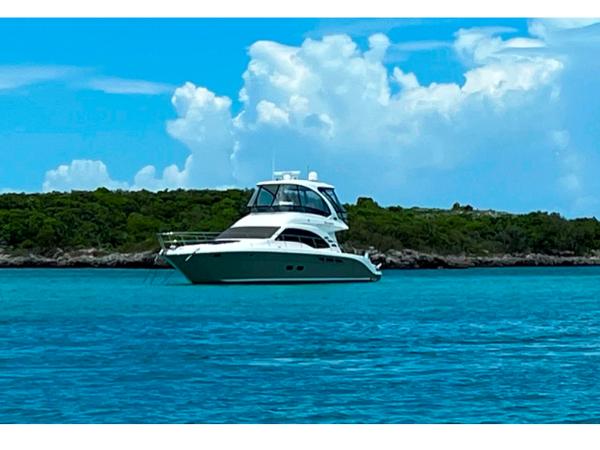 Sea Ray 52 Sedan Bridge 2006 Sea Ray 52 Sedan Bridge yacht on turquoise water with lush green island background.
