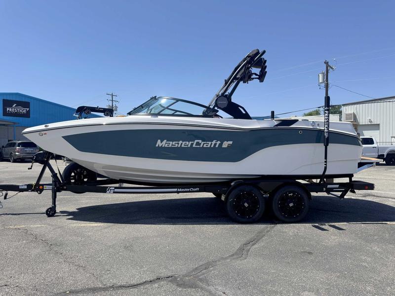 MasterCraft XT22 2025 MasterCraft XT22 boat on trailer, parked outdoors, side view.