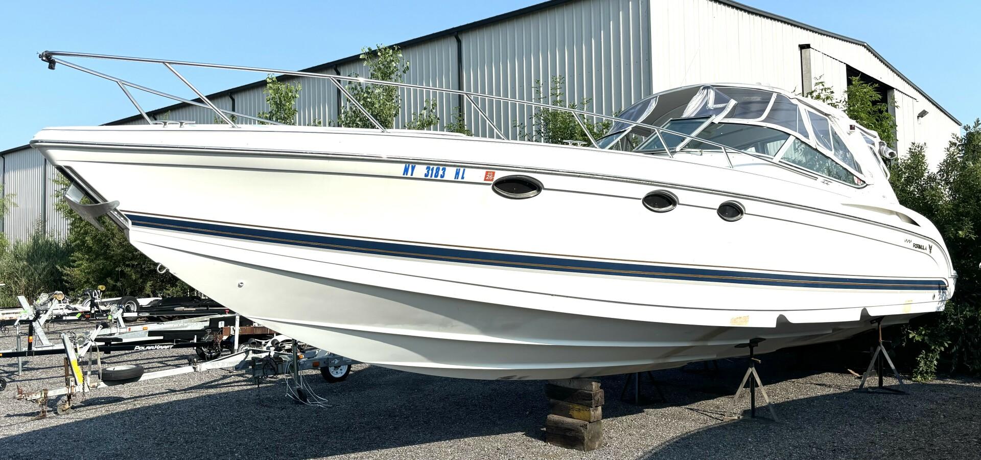 Formula 400 SS 2000 Formula 400 SS boat on stands, white exterior, parked outdoors near a warehouse.