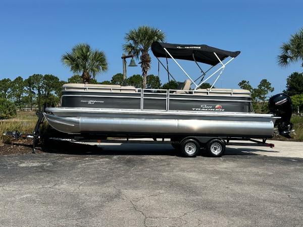Sun Tracker Party Barge 24 DLX 2024 Sun Tracker Party Barge 24 DLX pontoon boat on a trailer, parked outdoors.