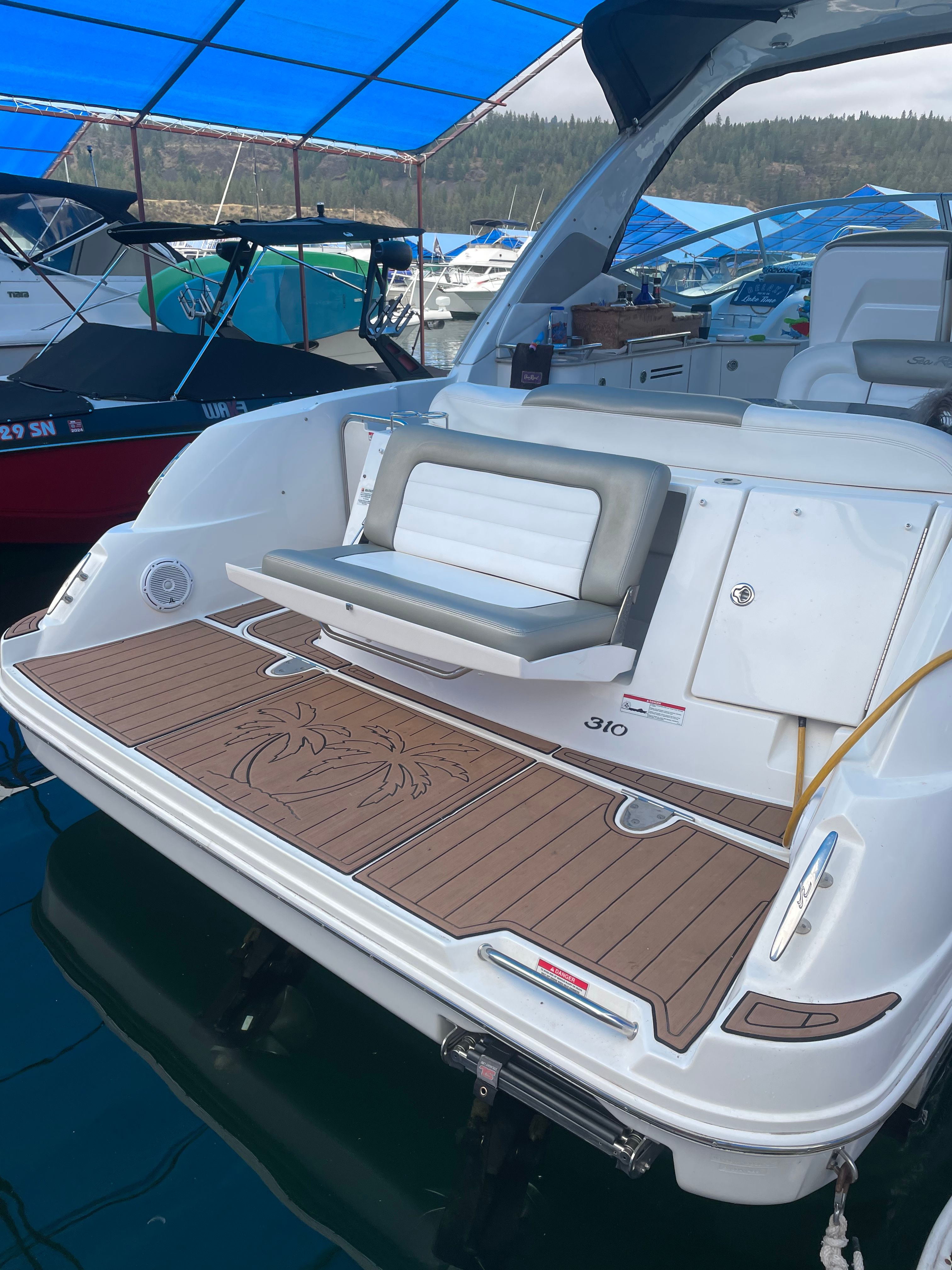 Sea Ray 310 Sundancer 2007 Sea Ray 310 Sundancer boat with teak swim platform and seating, docked under blue canopy.