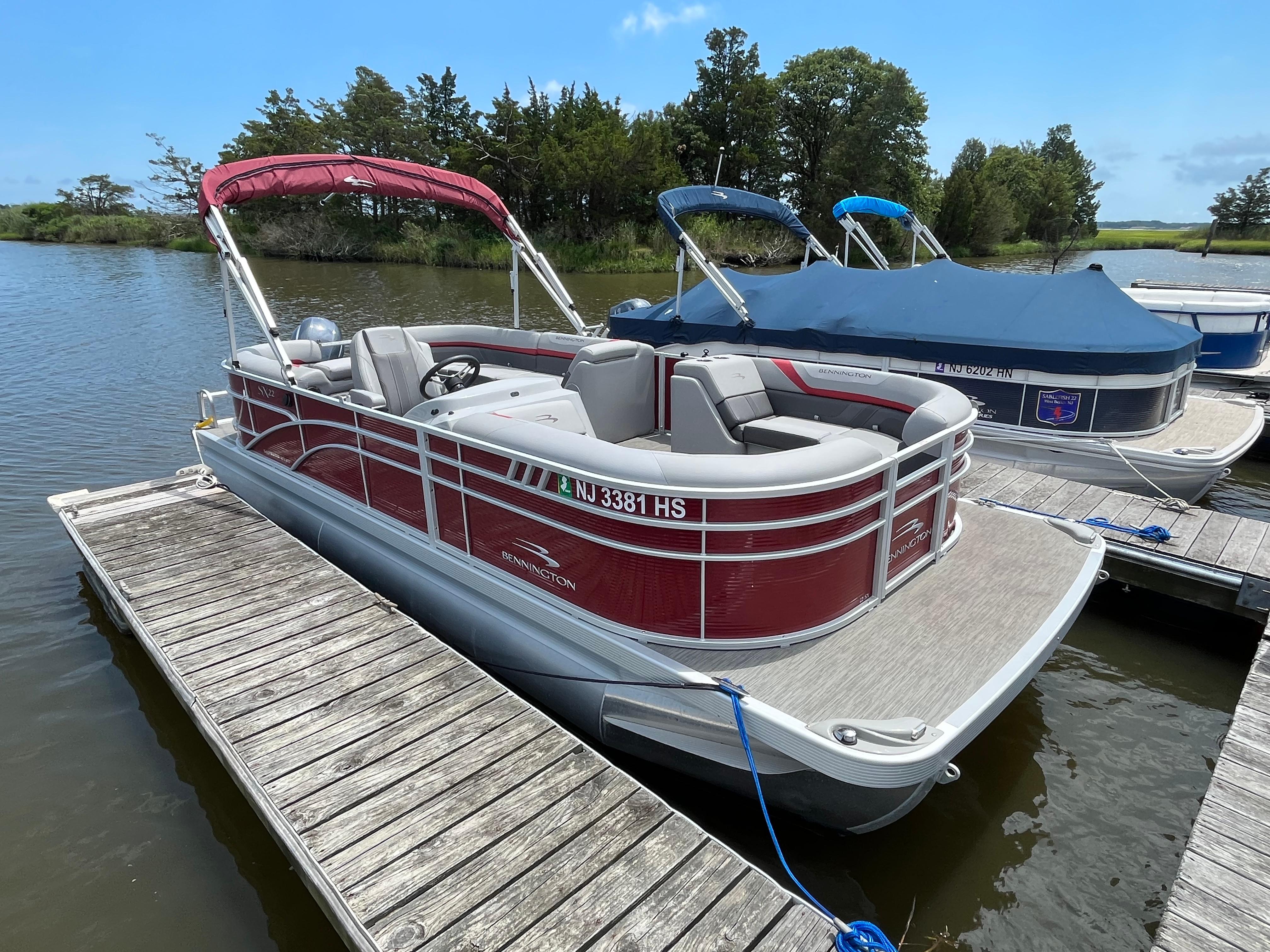 Bennington 22SSRCX 2022 Bennington 22SSRCX pontoon boat docked on a calm lake.