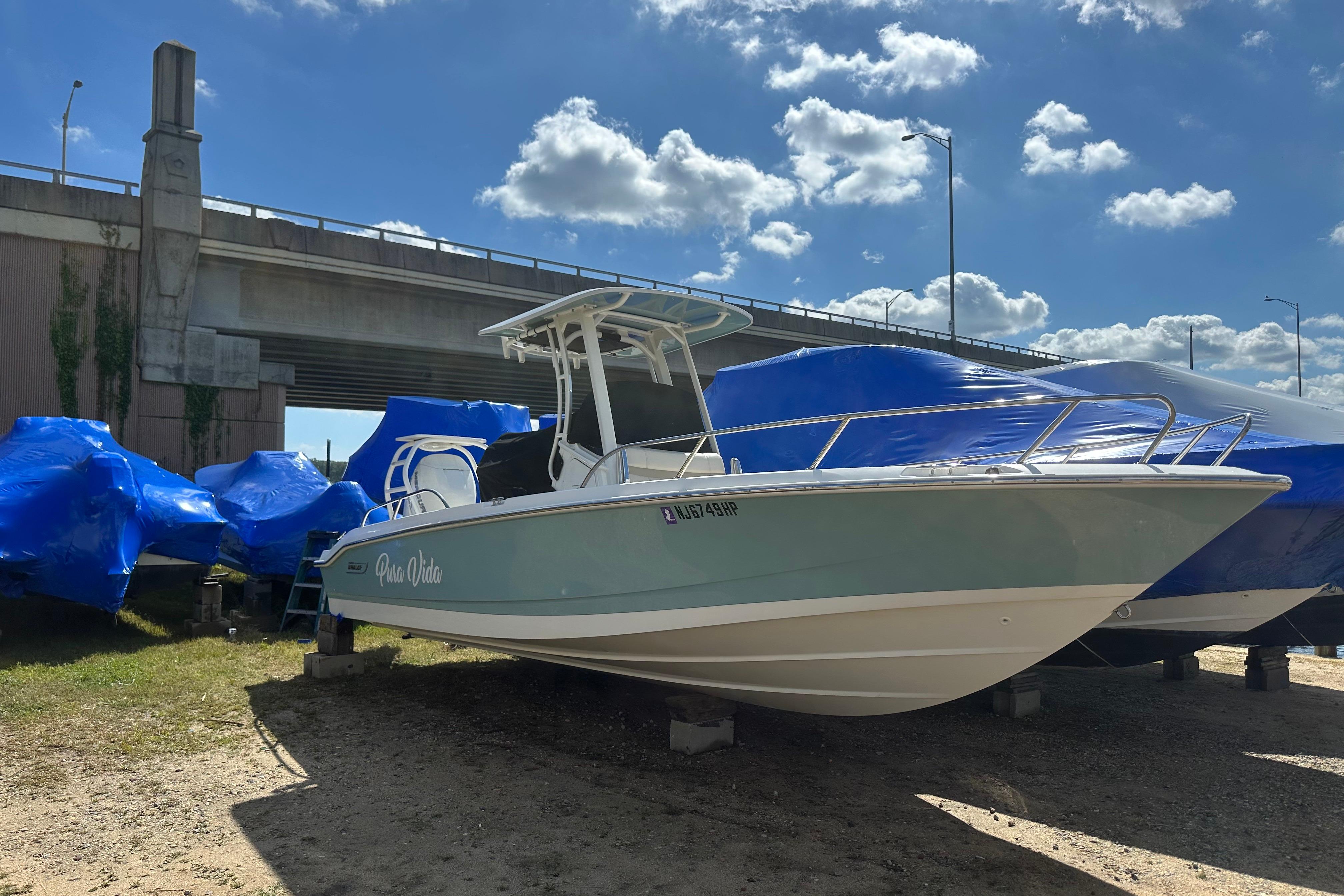 Boston Whaler 250 Dauntless 2021 Boston Whaler 250 Dauntless boat under a bridge, surrounded by blue tarps.