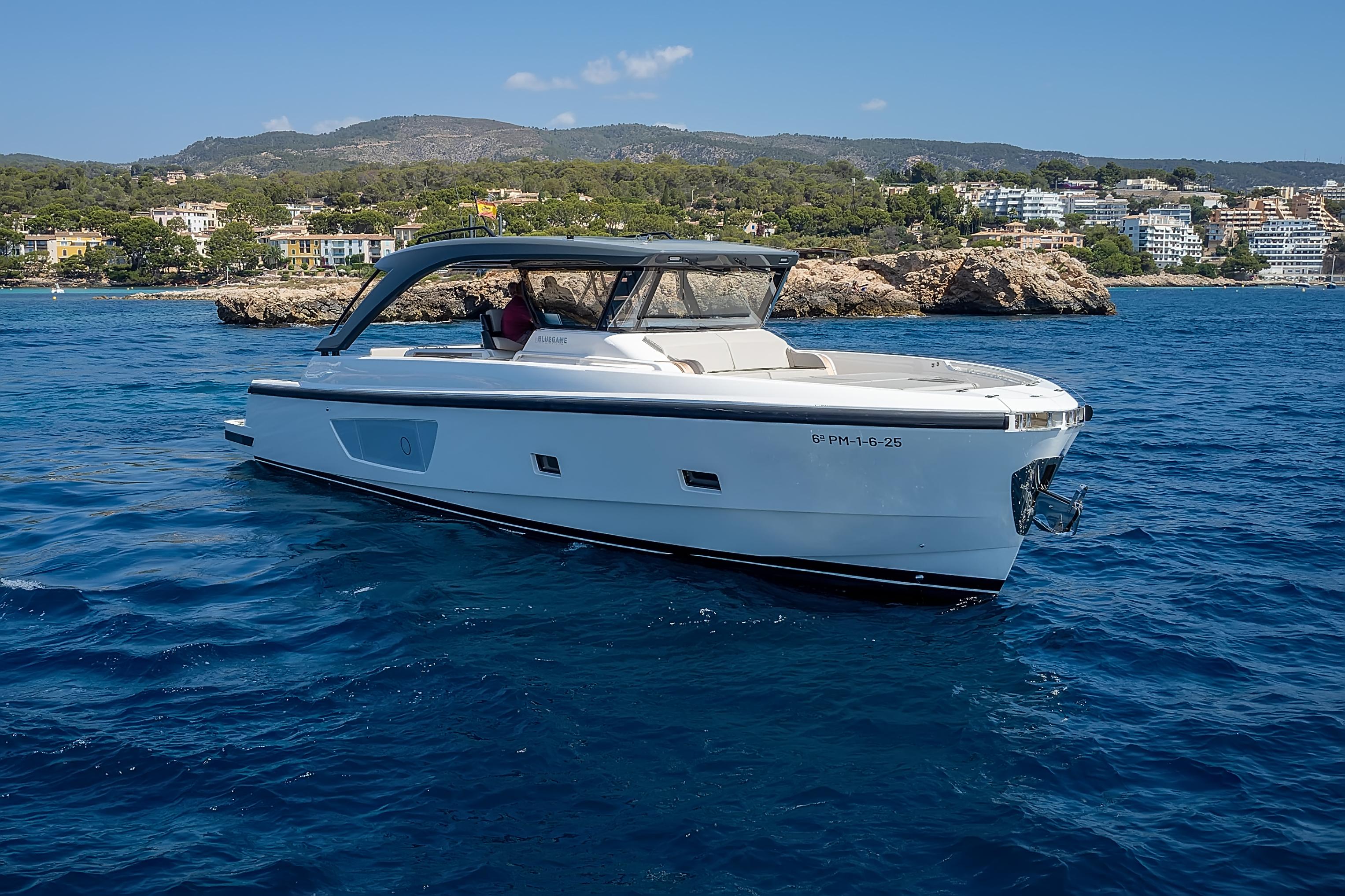 Bluegame 54 2024 Bluegame 54 yacht cruising on clear blue waters near a scenic coastline.