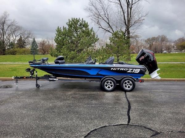 Nitro Z19 Pro 2024 Nitro Z19 Pro bass boat on trailer, blue and black, side view.