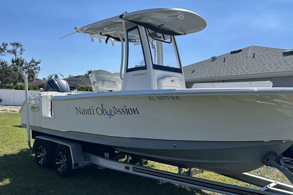 Sea Hunt Ultra 235 SE 2018 Sea Hunt Ultra 235 SE boat on trailer, named "Nauti Obsession," parked on grass.